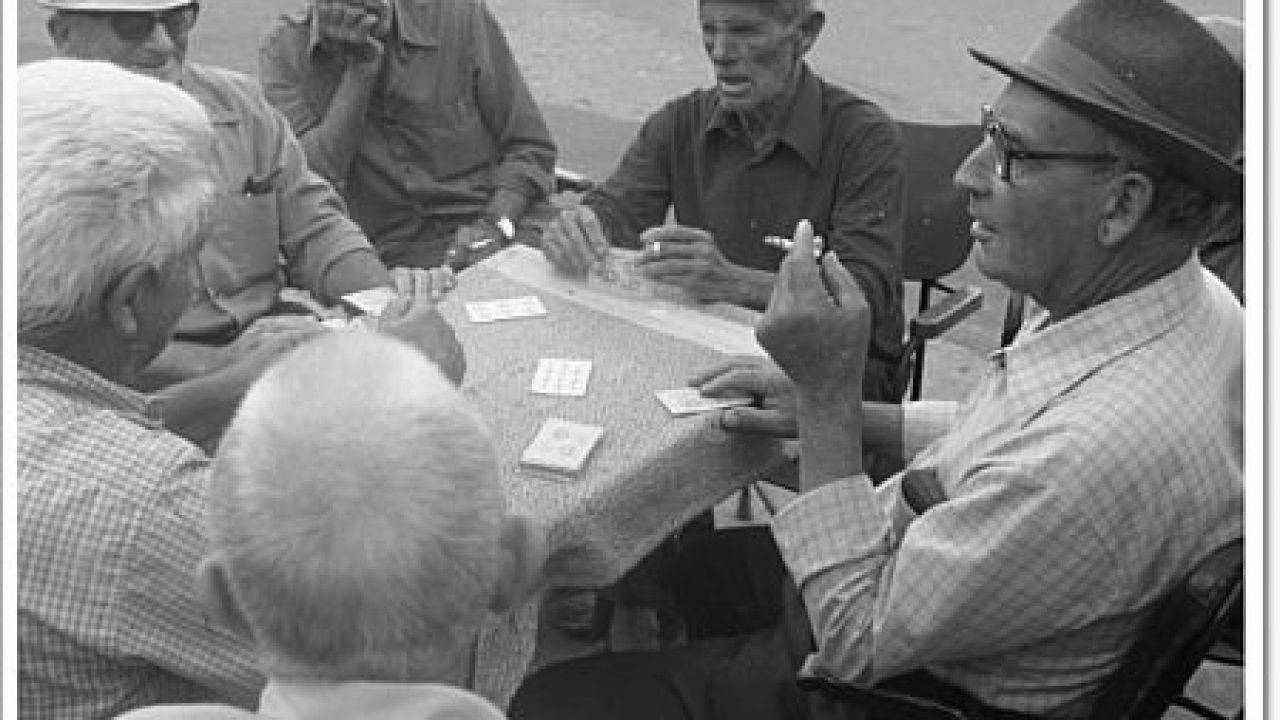 Six men playing a game of cards at a table in the street